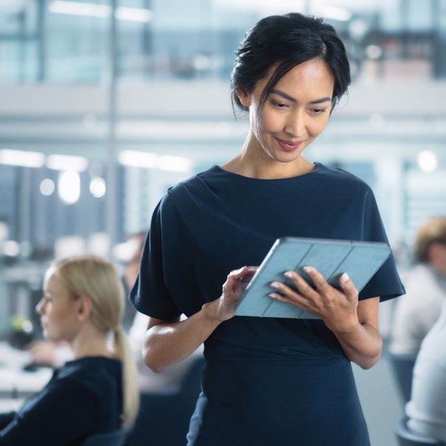 Successful,businesswoman,in,stylish,dress,using,tablet,computer,,standing,in