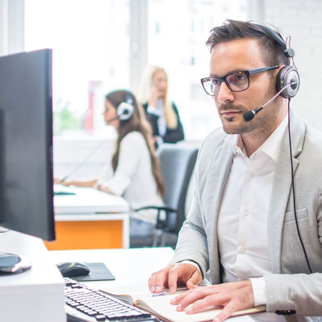 Serious Man Wearing Formal Clothes And Headset Looking At Computer Screen In Bright Office