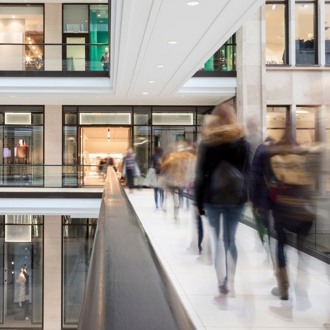 Shoppers Walking To The Mall With Stores And Shops